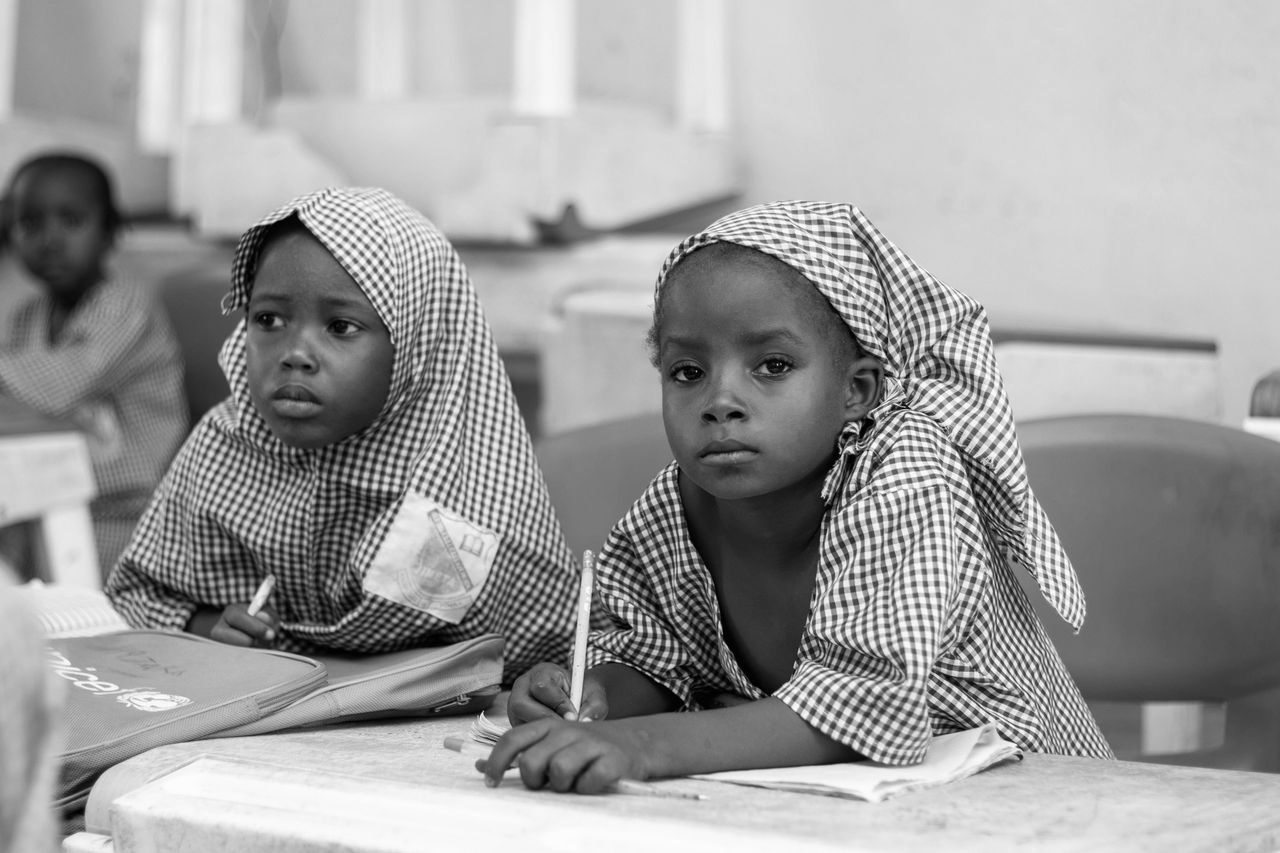 Services Black and white photo of young girls focusing on studies in a classroom.
